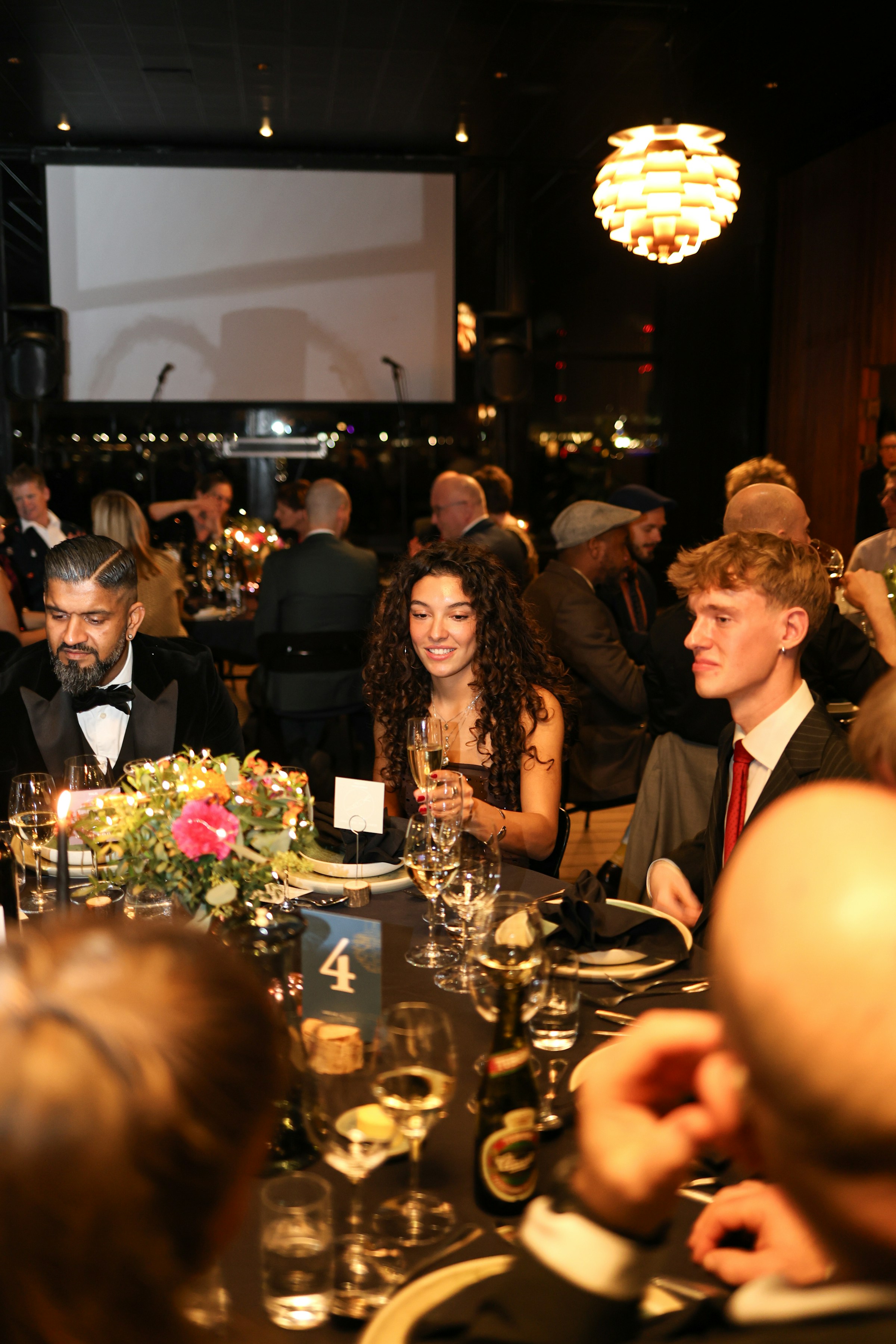 Guests seated at a formal awards dinner with a presentation screen